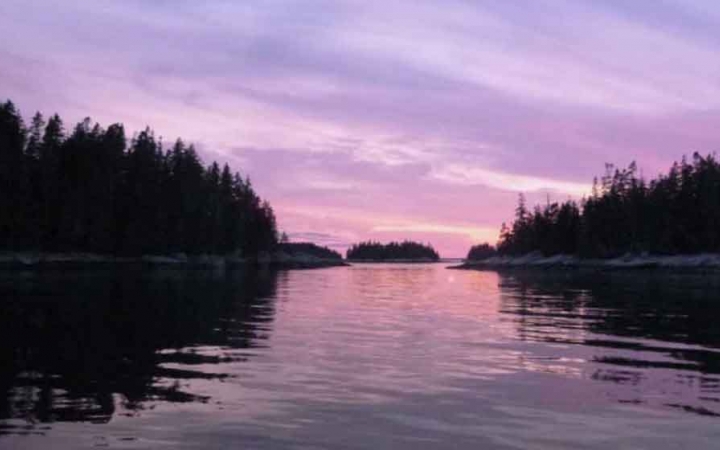 purple skies reflect off still water in maine